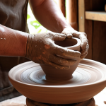 **Prompt 1: Skill & Foundation**
    "A close-up shot of a pottery artisan's hands, covered in clay, meticulously shaping a ceramic piece on a traditional pottery wheel in a sun-drenched, rustic workshop. In the background, shelves are filled with various stages of pottery, from raw clay forms to beautifully glazed finished products, symbolizing the blend of traditional techniques and continuous learning. The atmosphere is focused and dedicated, with soft, natural lighting emphasizing texture and detail."